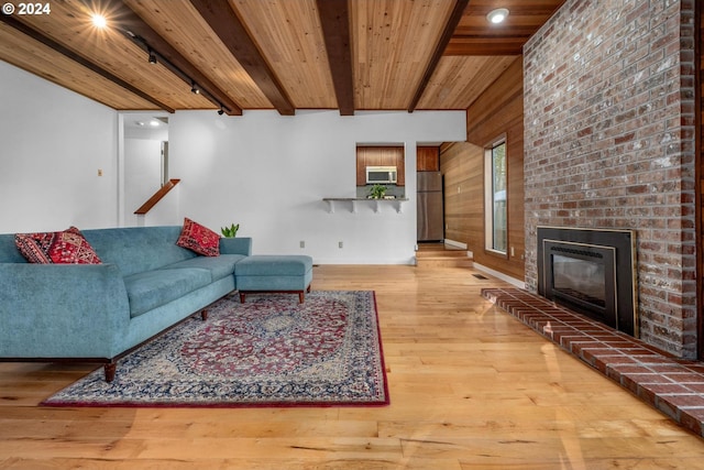 living room featuring wood walls, a brick fireplace, hardwood / wood-style flooring, beamed ceiling, and wood ceiling