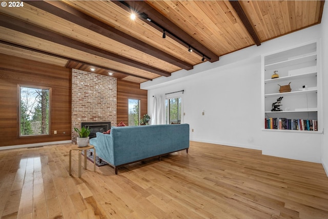 living room with light wood-type flooring, a fireplace, wooden walls, wooden ceiling, and beamed ceiling