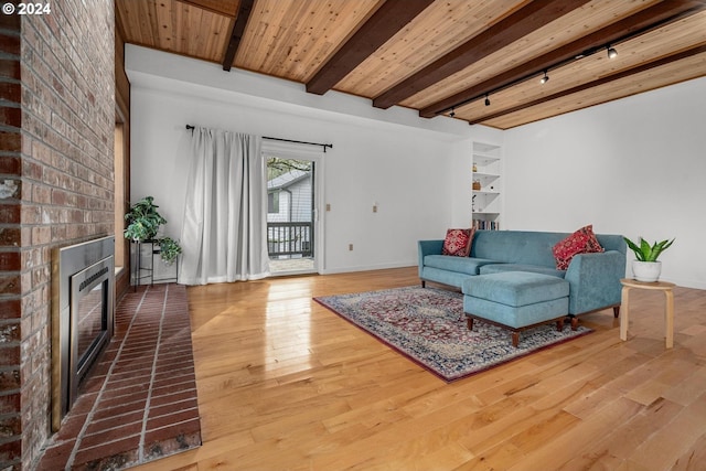 living room with track lighting, a fireplace, wood ceiling, beamed ceiling, and hardwood / wood-style floors