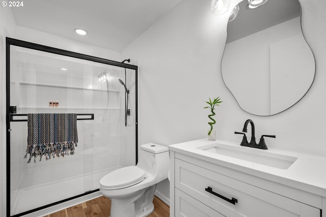 bathroom featuring hardwood / wood-style flooring, vanity, toilet, and a shower with shower door