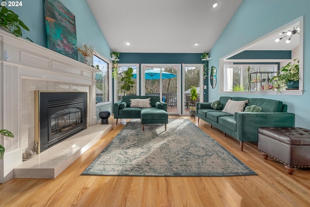 living room featuring a tiled fireplace, light hardwood / wood-style flooring, and lofted ceiling