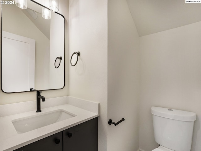 bathroom with vanity, toilet, and vaulted ceiling