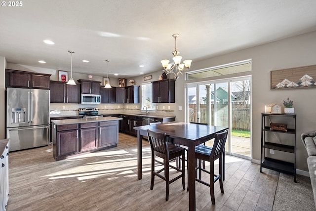 dining space with sink, an inviting chandelier, and light wood-type flooring