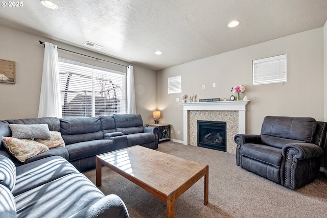 living room featuring carpet floors, a fireplace, and a textured ceiling