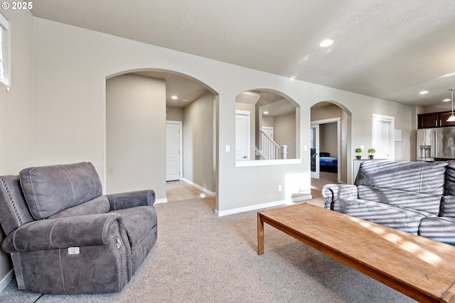 living room with recessed lighting, light colored carpet, stairs, and baseboards