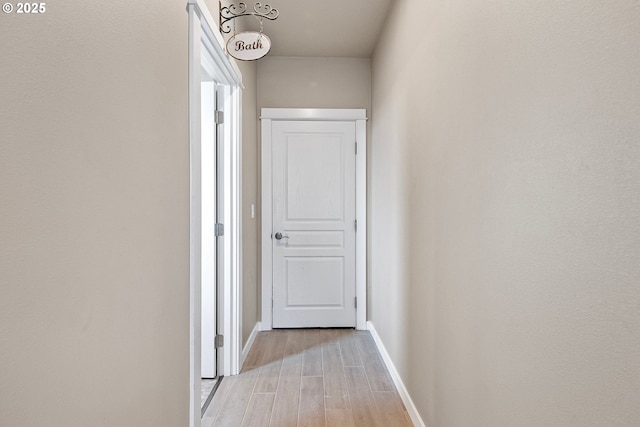 hallway featuring light wood-style flooring and baseboards