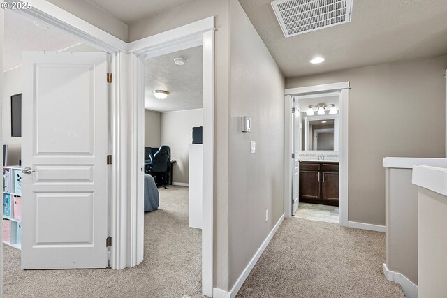 hallway featuring light colored carpet and a textured ceiling