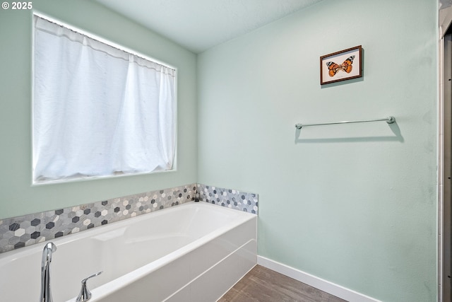 full bathroom with a garden tub, wood finished floors, baseboards, and a wealth of natural light