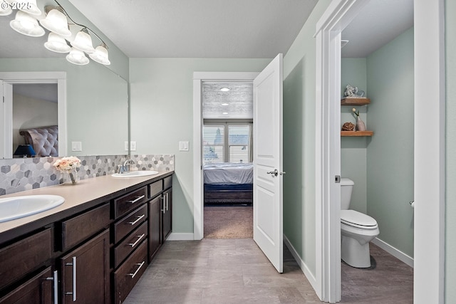 ensuite bathroom featuring toilet, tasteful backsplash, ensuite bathroom, and a sink