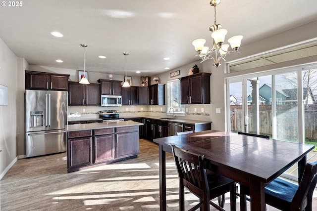 kitchen featuring a sink, dark brown cabinetry, light countertops, light wood-style floors, and appliances with stainless steel finishes