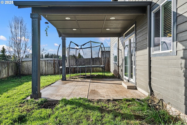 view of patio with a carport, a trampoline, and a fenced backyard