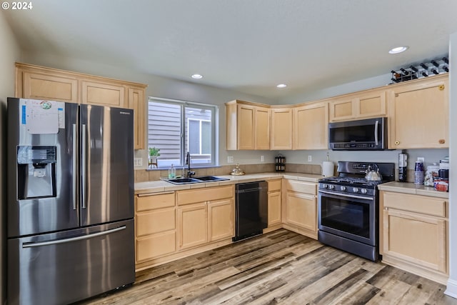 kitchen featuring black appliances, sink, light wood-type flooring, light brown cabinetry, and tile counters