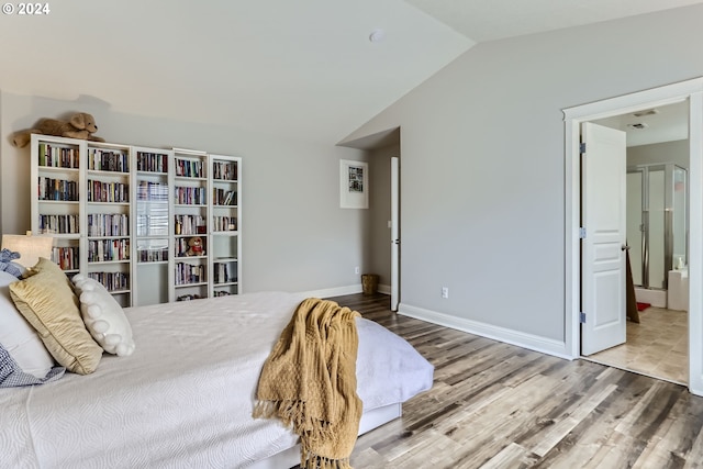 bedroom featuring ensuite bath, vaulted ceiling, and hardwood / wood-style flooring