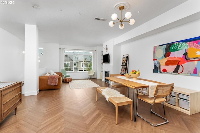 dining area with parquet flooring, a notable chandelier, and a textured ceiling