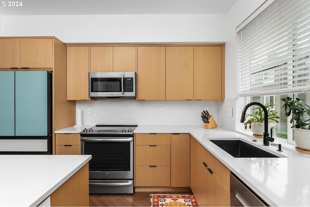 kitchen with tasteful backsplash, sink, light brown cabinets, and appliances with stainless steel finishes