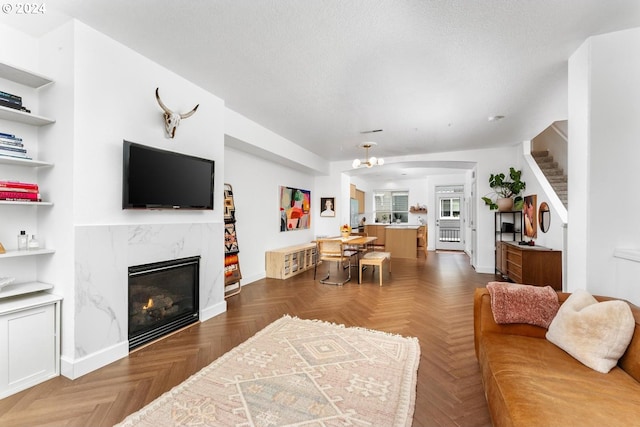 living room with a premium fireplace, dark parquet flooring, a textured ceiling, and built in shelves