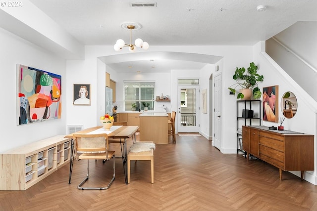 dining room featuring a textured ceiling, parquet flooring, and a chandelier