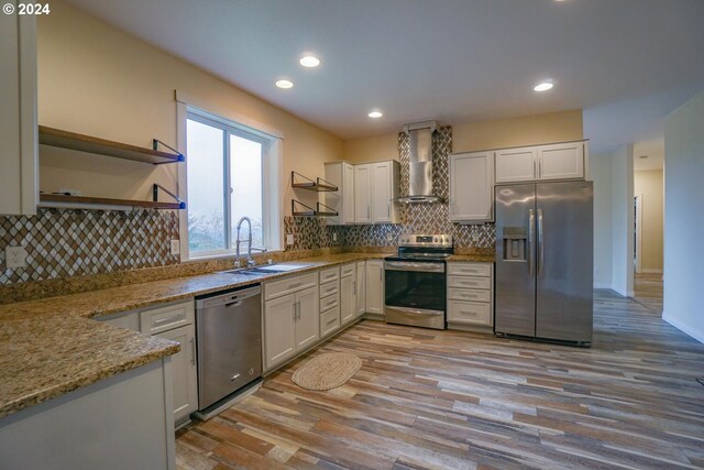 kitchen featuring white cabinetry, sink, wall chimney range hood, and appliances with stainless steel finishes