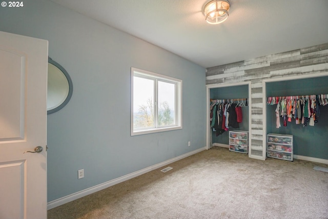 unfurnished bedroom featuring carpet and wooden walls