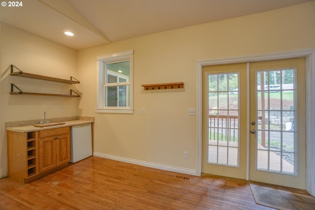 doorway to outside with sink, light wood-type flooring, and french doors