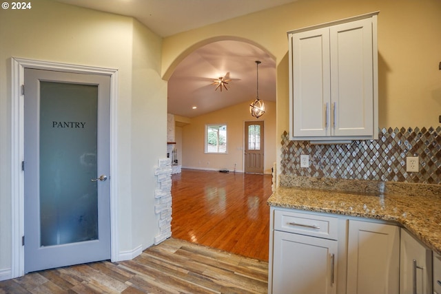 kitchen with decorative backsplash, white cabinets, light hardwood / wood-style flooring, and vaulted ceiling