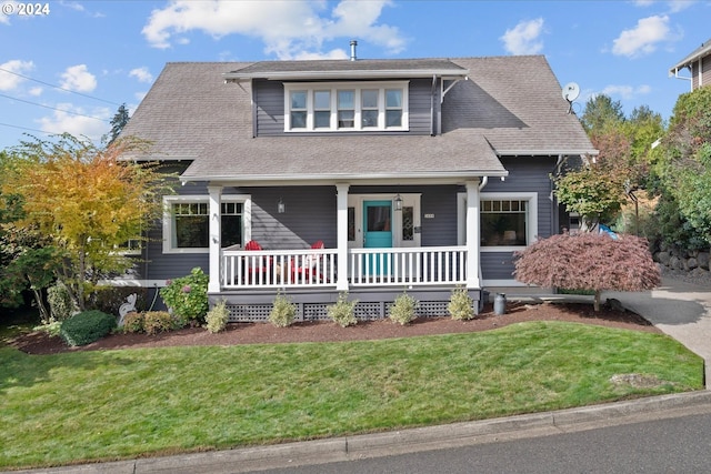 view of front of property with a porch, roof with shingles, and a front yard