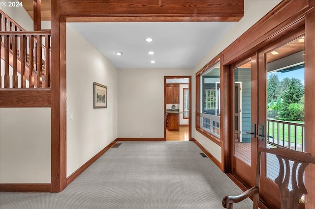 corridor with beamed ceiling, french doors, and light colored carpet