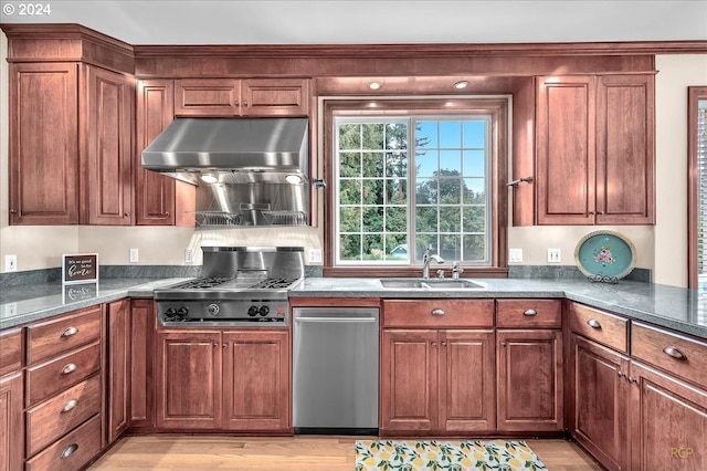 kitchen featuring sink, light wood-type flooring, stainless steel gas cooktop, dark stone counters, and range hood