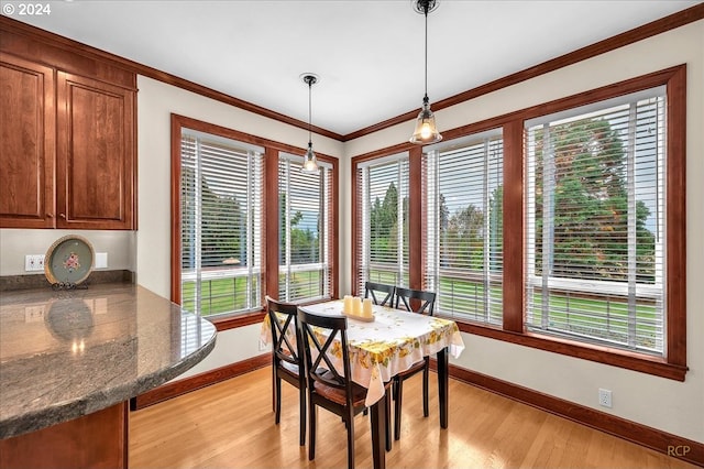 dining room with light hardwood / wood-style flooring, a healthy amount of sunlight, and crown molding