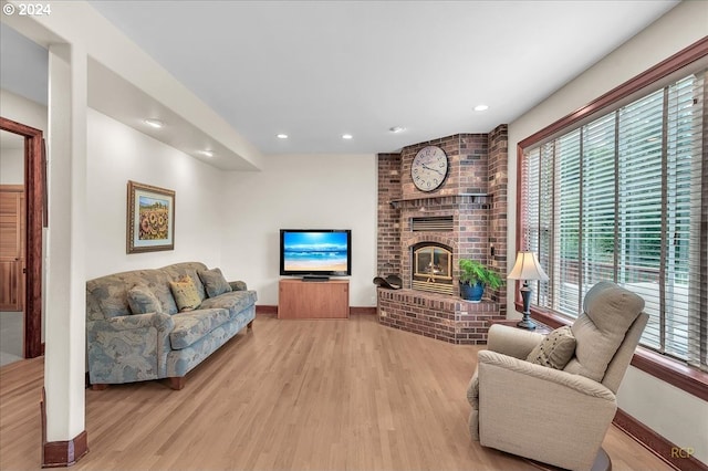 living room with light hardwood / wood-style floors, plenty of natural light, and a brick fireplace