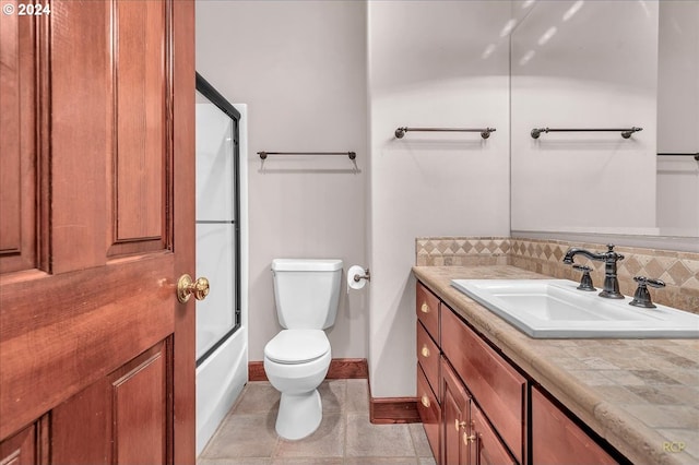 full bathroom with vanity, bath / shower combo with glass door, toilet, and tile patterned flooring