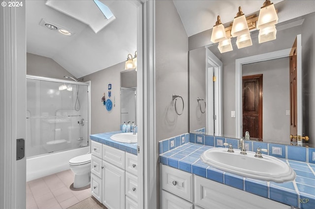 full bathroom featuring combined bath / shower with glass door, toilet, vaulted ceiling with skylight, vanity, and tile patterned flooring