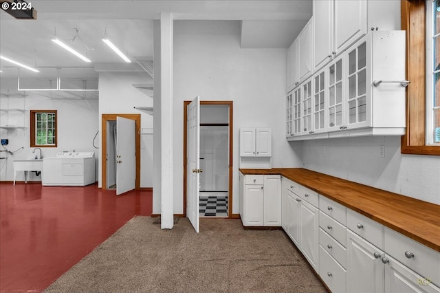 kitchen with sink, white cabinetry, washer and dryer, and wood counters