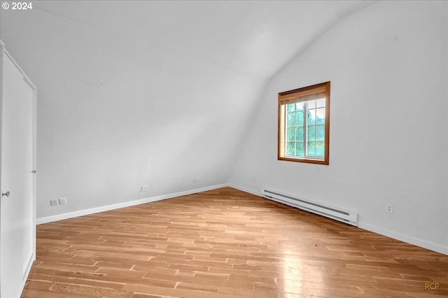 empty room with a baseboard heating unit, light wood-type flooring, and vaulted ceiling