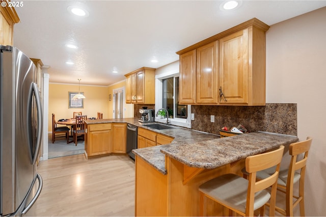 kitchen featuring kitchen peninsula, sink, pendant lighting, and appliances with stainless steel finishes