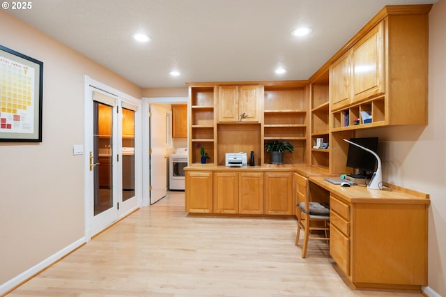 home office with light hardwood / wood-style floors, washer / dryer, and built in desk