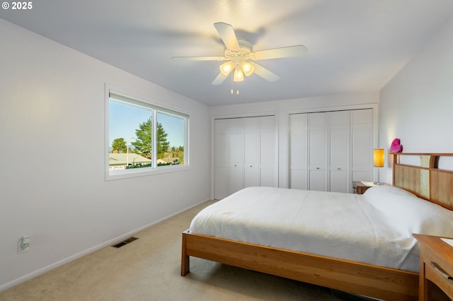 carpeted bedroom with ceiling fan and multiple closets