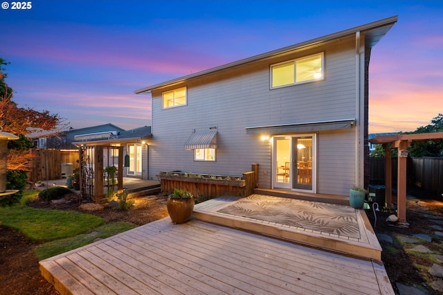 back house at dusk with a wooden deck