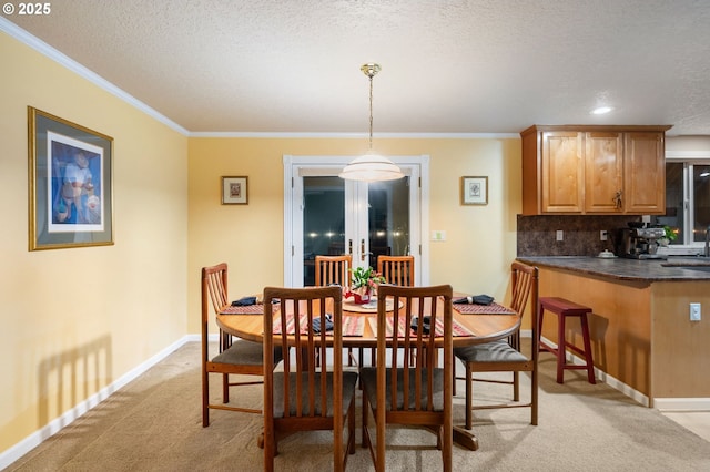 carpeted dining room featuring french doors, sink, a textured ceiling, and ornamental molding