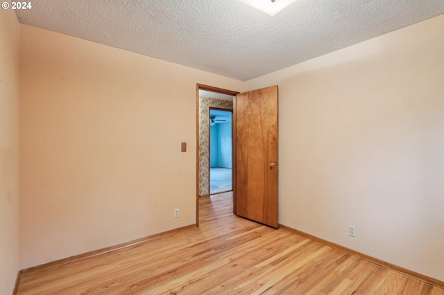 unfurnished room with light hardwood / wood-style floors, ceiling fan, and a textured ceiling