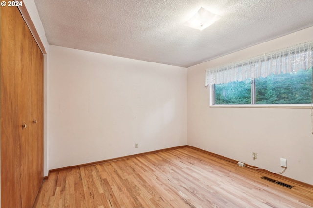 unfurnished bedroom with a textured ceiling, light hardwood / wood-style floors, and a closet