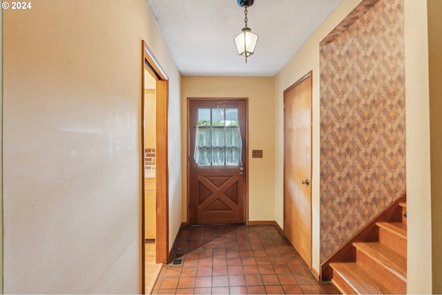 entryway with a textured ceiling and dark tile patterned flooring