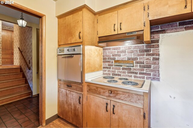 kitchen featuring pendant lighting, white electric cooktop, stainless steel oven, and light tile patterned floors