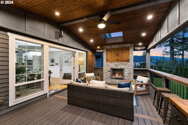 deck at dusk with ceiling fan and an outdoor living space with a fireplace