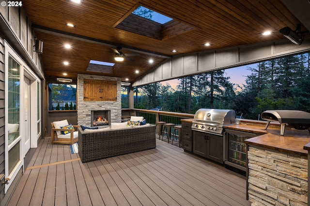 deck at dusk featuring an outdoor living space with a fireplace and area for grilling