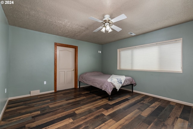 bedroom featuring ceiling fan, dark hardwood / wood-style flooring, and a textured ceiling