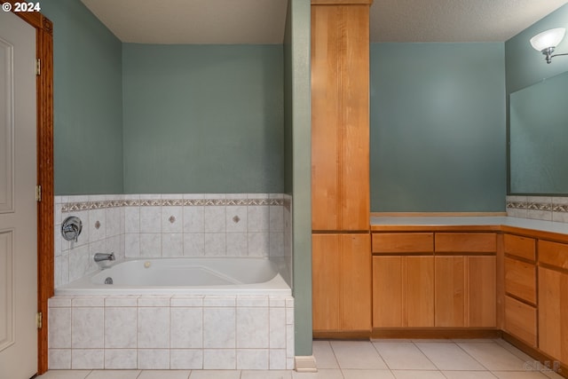 bathroom with tile patterned floors, a relaxing tiled tub, and a textured ceiling