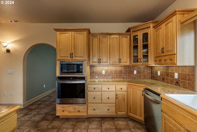 kitchen with decorative backsplash, appliances with stainless steel finishes, and a textured ceiling