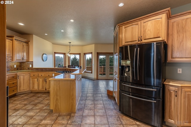 kitchen featuring light brown cabinetry, tasteful backsplash, decorative light fixtures, fridge with ice dispenser, and a kitchen island