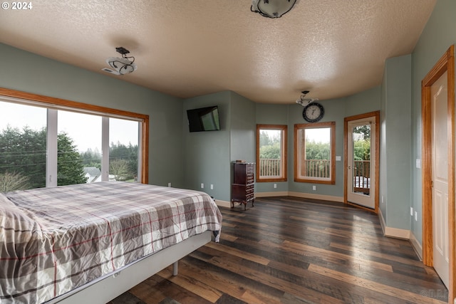 bedroom with access to exterior, a textured ceiling, and dark hardwood / wood-style floors